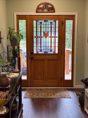Wood front door with a leaded glass window in a Frank Lloyd Wright design and matching transom above